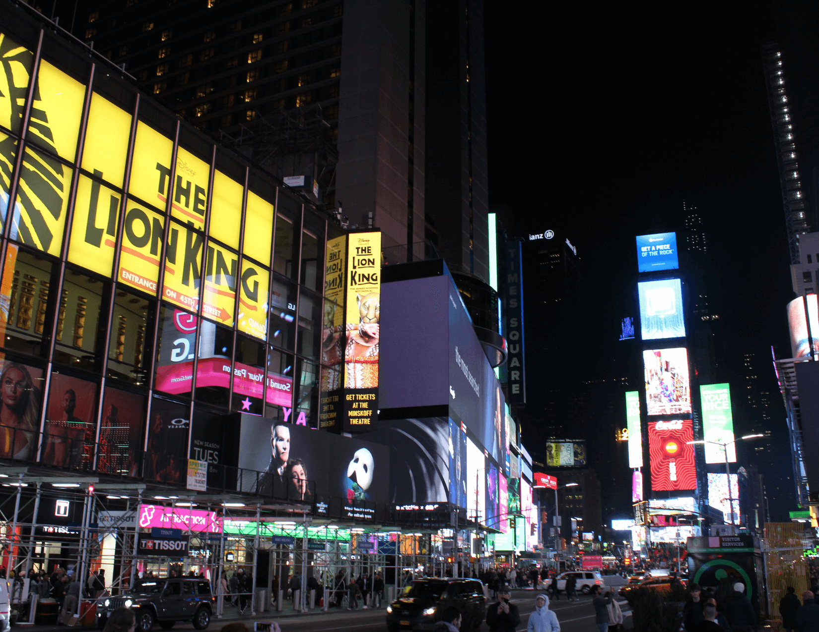 New York City street at night with the Lion King Musical marquee and billboards 